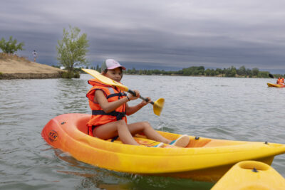Photo d'une jeune fille qui rame sur son kayak, le ciel est gris sombre au loin - Agrandir l'image 4 sur 16, fenêtre modale