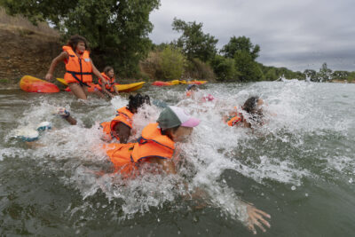 Photo des enfants avec leurs gilets de sauvetage qui sautent dans l'eau - Agrandir l'image 7 sur 16, fenêtre modale