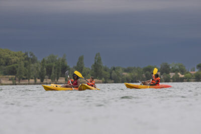 Photo de quelques enfants avec l'animateur dans leurs kayaks sur le lac, au loin le ciel est gris - Agrandir l'image 12 sur 16, fenêtre modale