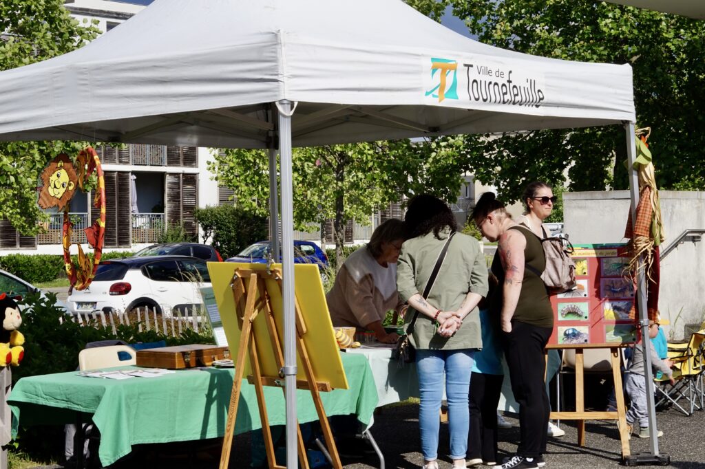 Photo d'un stand en extérieur avec des personnes devant - Agrandir l'image, fenêtre modale