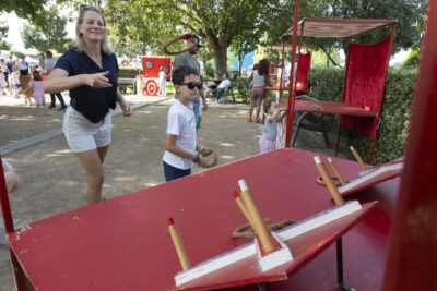 Photo d'une femme et d'un jeune garçon qui joue à un jeu dans un parc, ils doivent lancer un objet circulaire sur des bâtons en face d'eux - Agrandir l'image 7 sur 22, fenêtre modale