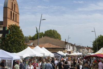 Photo de la rue Doumergue au niveau du rond-point devant la Mairie, avec vue sur l'église et la foule dans la rue - Agrandir l'image 9 sur 22, fenêtre modale