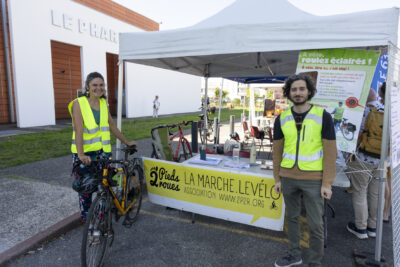 photo du stand associatif de 2 pieds 2 roues, une femme et un homme posent devant, ils portent un gilet jaune et la femme tient son vélo à côté d'elle - Agrandir l'image 10 sur 68, fenêtre modale