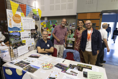 photo du stand de la guinguette avec quatre personnes derrière qui sourient à l'objectif, sur la table, des photos de la guinguette - Agrandir l'image 24 sur 68, fenêtre modale