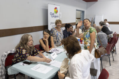 photo des stands du club de langue, une vingtaine de personnes en train d'échanger aux différentes tables réparties par langue - Agrandir l'image 36 sur 68, fenêtre modale