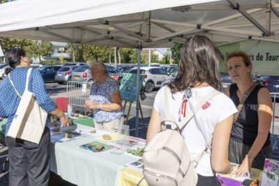 photo de deux stands associatifs, derrière chacun d'eux une femme qui échange avec une autre femme qu'on voit de dos - Agrandir l'image 4 sur 68, fenêtre modale