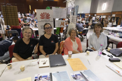 photo du stand stretching postures énergie, quatre femmes assises derrière le stand sourient à l'objectif - Agrandir l'image 54 sur 68, fenêtre modale