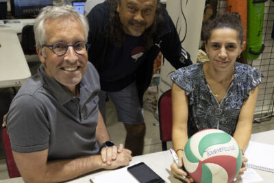 photo d'un stand avec trois personnes qui sourient à l'objectif, une jeune femme tient un ballon dans ses mains, posées sur la table - Agrandir l'image 57 sur 68, fenêtre modale