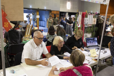 photo du stand des tumbleweeds avec trois personnes derrière en train d'échanger avec une femme - Agrandir l'image 66 sur 68, fenêtre modale
