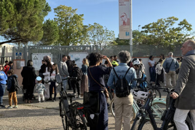 Photo de familles réunies, avec des vélos pour certaines, devant le portail du collège Labitrie, sous un ciel bleu - Agrandir l'image 13 sur 80, fenêtre modale