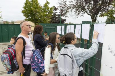 un père et deux jeunes filles devant les grilles de l'école, une fille regarde une liste de classe - Agrandir l'image 42 sur 80, fenêtre modale