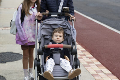 une femme et ses deux enfants, sa fille à côté d'elle et elle tient la poussette avec un autre enfant, sur le trottoir - Agrandir l'image 54 sur 80, fenêtre modale
