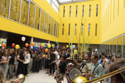 photo dans un hall jaune, avec des verrières au plafond, un groupe de musique joue et des lycéens autour écoutent - Agrandir l'image 58 sur 80, fenêtre modale