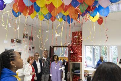 photo dans une salle avec des ballons qui flottent sous le plafond, deux élèves au premier plan et derrière le Maire et des élus, la directrice - Agrandir l'image 6 sur 80, fenêtre modale