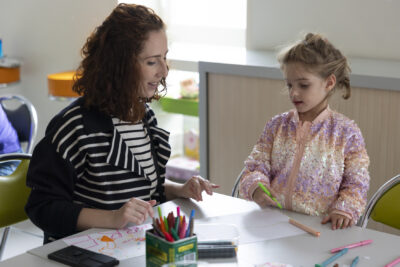 Photo d'une femme et d'une petite fille assises à table, la petite fille dessine sur une feuille en papier - Agrandir l'image 14 sur 21, fenêtre modale