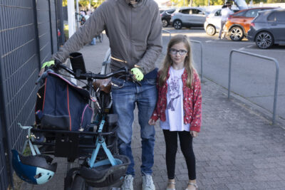 Photo d'un homme à pieds avec son vélo qu'il tient par le guidon avec sa fille à côté de lui - Agrandir l'image 25 sur 80, fenêtre modale