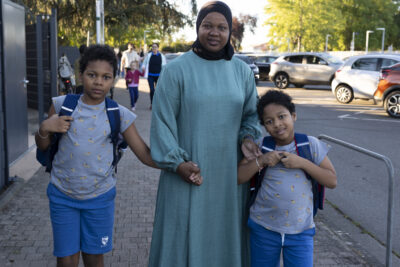 photo d'une femme avec ses deux enfants qu'elle tient par la main, sur le trottoir - Agrandir l'image 26 sur 80, fenêtre modale