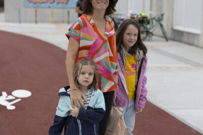 Une femme est ses deux filles sur un passage piéton devant l'école, tout sourire - Agrandir l'image 39 sur 80, fenêtre modale