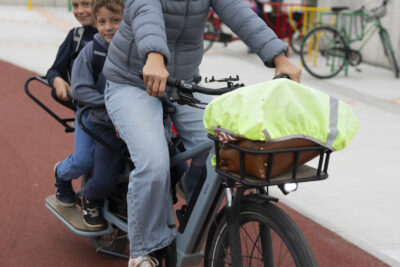 une femme à vélo cargo avec deux enfants à l'arrière, arrive sur la piste cyclable - Agrandir l'image 31 sur 80, fenêtre modale