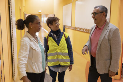 le maire, la première adjointe et la directrice échangent joyeusement dans un couloir orange - Agrandir l'image 76 sur 80, fenêtre modale
