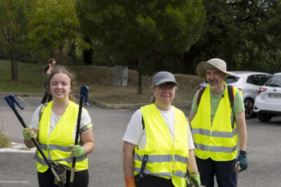 Photo de trois personnes en gilets jaunes avec des pinces pour ramasser les déchets, sur un parking - Agrandir l'image 14 sur 16, fenêtre modale