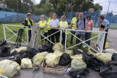 Photo de groupe d'une dizaine de personnes rassemblées derrière une barrière blanche, devant une vingtaine de sacs poubelle pleins - Agrandir l'image 15 sur 16, fenêtre modale