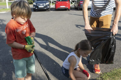 photo portrait d'un homme et de deux enfants, l'homme tient un sac poubelle, une petite fille s'agenouille pour ramasser un mégot, un petit garçon à côté tient une pince - Agrandir l'image 6 sur 16, fenêtre modale