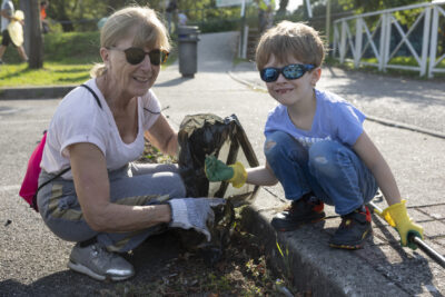 Photo paysage d'une femme et d'un petit garçon, agenouillés en train de ramasser des déchets sur un parking - Agrandir l'image 1 sur 16, fenêtre modale