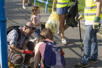 Photo portrait d'un groupe de personnes, adultes et enfants, qui ramassent des déchets à proximité d'un terrain sportif - Agrandir l'image 4 sur 16, fenêtre modale