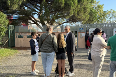 Photo du Maire qui échange avec une famille devant le collège - Agrandir l'image 15 sur 80, fenêtre modale