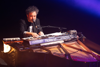 sur scène dans la semi-obscurité, au micro penché sur son piano l'artiste est absorbé par son jeu - Agrandir l'image, fenêtre modale