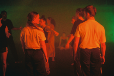 PHOTO SEPIA D UN GROUPE DE DANSEURS DEBOUT SUR UNE PISTE DE DANSE EN TEE SHIRT BLANC ET JEANS