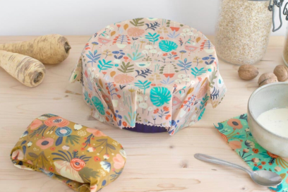 photo de Bee wraps ou film alimentaire réalisé à base cire d'abeille joliment décoré de motifs floraux et colorés, disposés sur une table en bois naturel - Agrandir l'image, fenêtre modale