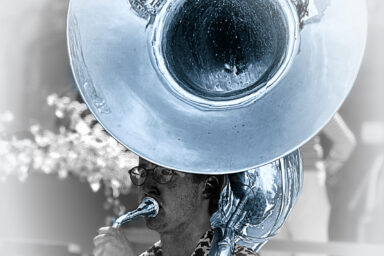 Photo de colorimétrie gris bleu d'un homme qui joue d'un instrument à vent qu'il tient à l'épaule