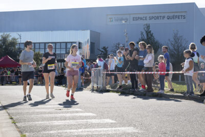 trois jeunes qui courent sur le parking de l'espace sportif de Quéfets sous les applaudissements des gens rassemblés derrière le ruban de sécurité - Agrandir l'image 9 sur 23, fenêtre modale
