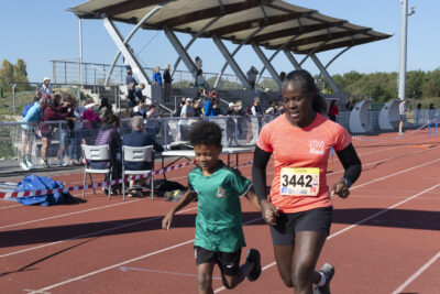 une femme et un jeune garçon courent ensemble sur la piste d'athlétisme, ils s'apprêtent à franchir la ligne d'arrivée - Agrandir l'image 17 sur 23, fenêtre modale