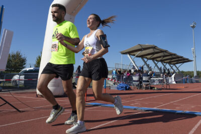un couple d'un homme et d'une femme franchit la ligne d'arrivée, elle sourit, sur la piste d'athlétisme - Agrandir l'image 18 sur 23, fenêtre modale