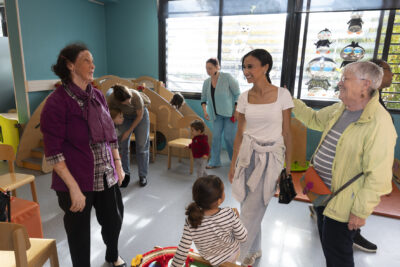 photo paysage de trois femmes qui discutent sans une ludothèque, on voit aussi des enfants qui jouent sur les jeux - Agrandir l'image 7 sur 19, fenêtre modale