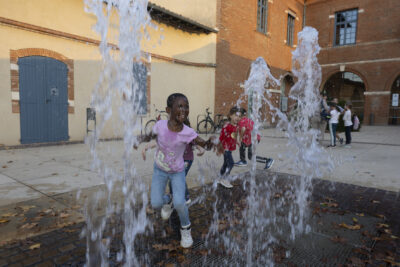 photo d'un enfant qui joue avec les jets d'eau sur le parvis de la Mairie - Agrandir l'image 16 sur 20, fenêtre modale