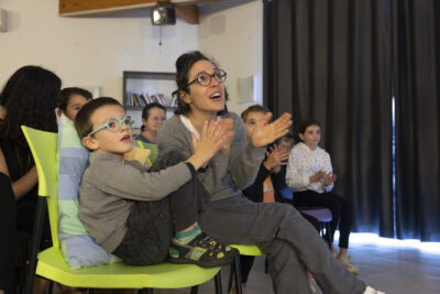une femme et un petit garçon assis avec d'autres familles applaudissent - Agrandir l'image 9 sur 20, fenêtre modale