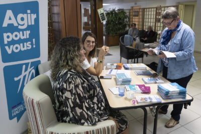 une femme âgée se renseigne auprès d'un stand, elle consulte de la documentation - Agrandir l'image 7 sur 20, fenêtre modale