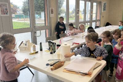 photo d'enfants qui récupèrent leurs outils pour peindre, il y a des rouleaux en bois, des sortes de brosses pour nettoyer les vitres, sur une table - Agrandir l'image 8 sur 10, fenêtre modale