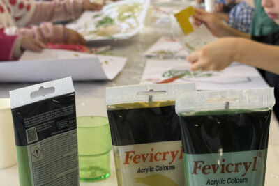 photo avec le focus au premier plan sur les tubes de peinture acrylique et à l'arrière plan sur les enfants assis en train de peindre - Agrandir l'image 6 sur 10, fenêtre modale