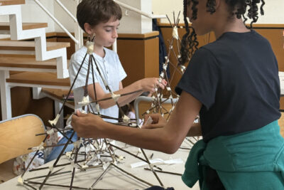 photo d'une jeune fille et d'un jeune garçon en train d'assembler chacun leur lanterne faite de branches fines accrochées ensemble par des scotchs - Agrandir l'image 7 sur 8, fenêtre modale