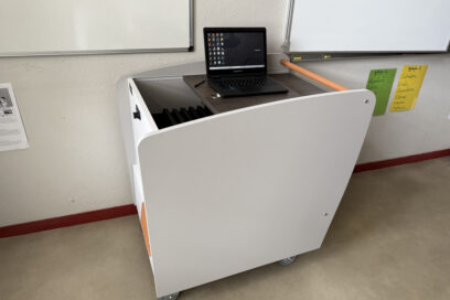 Photo paysage d'une classe mobile : meuble à roulette sur lequel un ordinateur portable est ouvert, situé devant des tableaux blancs dans une école - Agrandir l'image, fenêtre modale