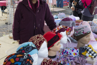 photo d'une femme qui vend des bonnets et couvre-chefs colorés à un stand sur le parvis - Agrandir l'image 19 sur 21, fenêtre modale