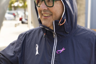 photo d'un homme souriant, vête d'un imperméable bleu foncé avec deux rubans accrochés dessus - Agrandir l'image 10 sur 21, fenêtre modale