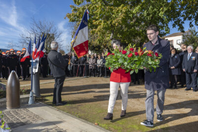 photo d'un homme et d'une femme qui s'apprêtent à déposer une gerbe de fleurs devant le monument aux morts - Agrandir l'image 11 sur 38, fenêtre modale