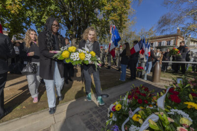 photo de deux jeunes femmes qui déposent une gerbe de fleurs devant le monument aux morts - Agrandir l'image 14 sur 38, fenêtre modale