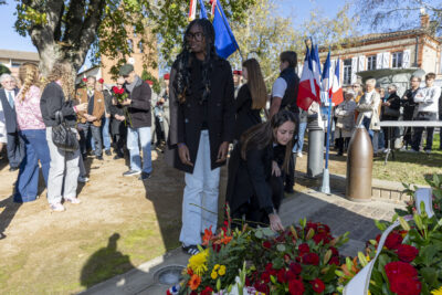 photo de deux jeunes femmes qui déposent une rose devant le monument aux morts - Agrandir l'image 19 sur 38, fenêtre modale